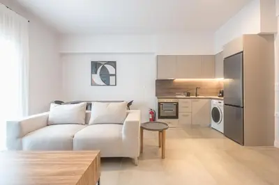 a living room with a white couch and a kitchen at Zografou Urban Apartments, A2Zen in Athens