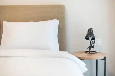 a bed with a white pillow and a lamp on a table at Zografou Urban Apartments, A2Zen in Athens
