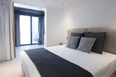 a bedroom with a large bed with pillows and a window at Penthouse in the Heart of Glyfada in Athens