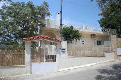 a white house with a gate and a fence at DAT Comfy house in Kalívia Thorikoú