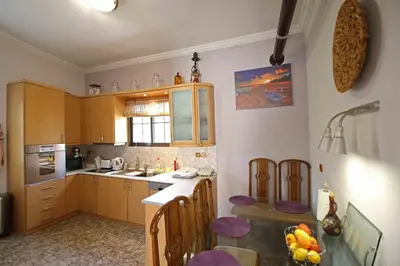 a kitchen with wooden cabinets and a table with chairs at DAT Comfy house in Kalívia Thorikoú