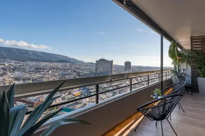 a balcony with two chairs and a view of a city at The HostMaster Skyline Tower View Suite in Athens