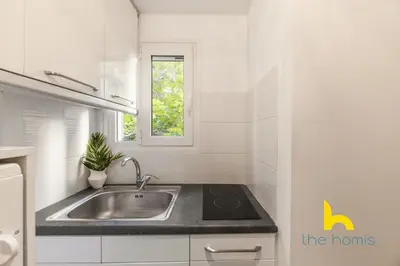a white kitchen with a sink and a window at Modern Studio Escape near Seaside & Marina! in Athens