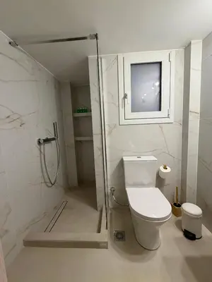 a bathroom with a toilet and a shower with a window at Kiafas 5 Apartment Athens in Athens