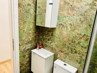 a bathroom with a white toilet and a wall at Brown balcony suite no 2 Piraeus Port in Piraeus