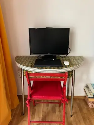 a computer monitor on a table with a red stool at Sweet Home Athens in Athens