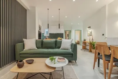 a living room with a green couch and a table at Peacefull Family APT W Sunny Balcony in Kallithea in Athens