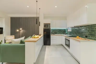 a kitchen with white cabinets and a green couch at Peacefull Family APT W Sunny Balcony in Kallithea in Athens