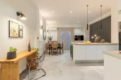 a kitchen and dining room with white cabinets and a table at Peacefull Family APT W Sunny Balcony in Kallithea in Athens
