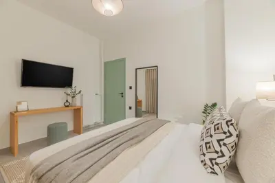 a white bedroom with a bed and a flat screen tv at Peacefull Family APT W Sunny Balcony in Kallithea in Athens