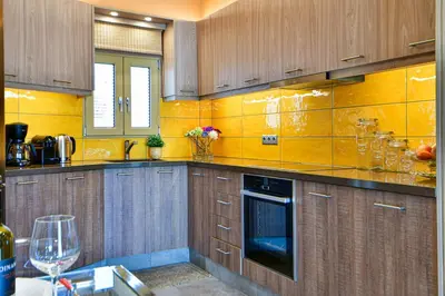 a kitchen with wooden cabinets and a yellow wall at Cosy modern flat under the Acropolis in Athens