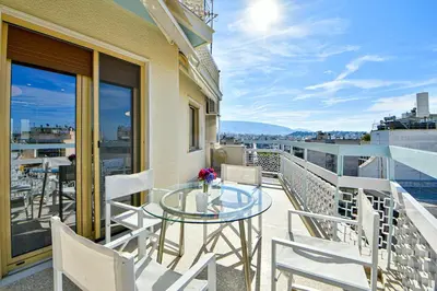 a balcony with a glass table and chairs at Cosy modern flat under the Acropolis in Athens