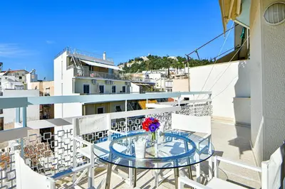 a balcony with a glass table and white chairs at Cosy modern flat under the Acropolis in Athens