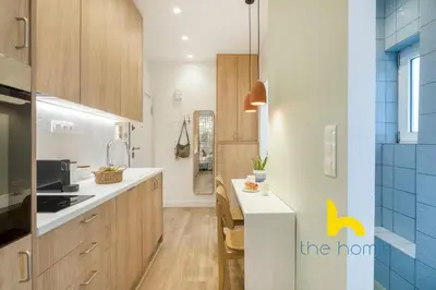 a kitchen with wooden cabinets and a dining table at Stylish Love Nest W Balcony in Heart of Koukaki! in Athens