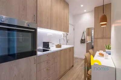 a kitchen with wooden cabinets and a black appliance at Stylish Love Nest W Balcony in Heart of Koukaki! in Athens