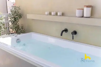 a bath tub with a faucet in a bathroom at Top-Floor Oasis, King-Bed & Whirlpool, Acropolis! in Athens