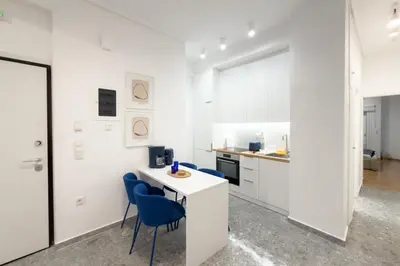a white kitchen with blue chairs and a white table at Ella's Athenian Home in Athens