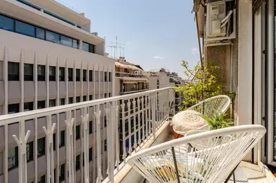 a balcony with two chairs and a table and a building at Amazing Luxurious BrandNew 4BDR 2Bath ΑcropolisAPT in Athens