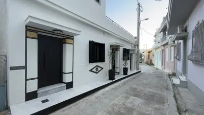 an alley with white buildings and a black door at Myronos suite with jacuzzi in Piraeus