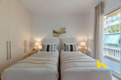 two beds in a room with a window at Chic Koukaki Haven Steps to Metro & Acropolis! in Athens