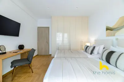 a bedroom with two beds and a desk and a tv at Chic Koukaki Haven Steps to Metro & Acropolis! in Athens