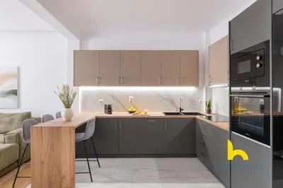 a kitchen with gray cabinets and a wooden table at Chic Koukaki Haven Steps to Metro & Acropolis! in Athens