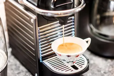 a cup of coffee is being poured into a coffee machine at Urban Piraeus, Apartment No 2 in Piraeus