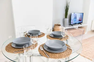 a glass table with plates and glasses and a tv at Urban Piraeus, Apartment No 2 in Piraeus