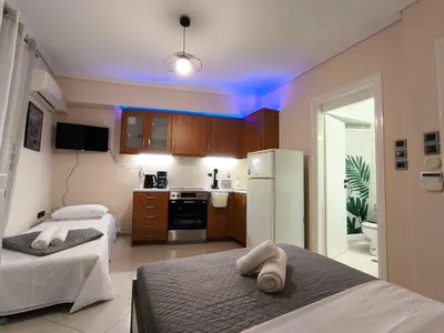 a room with two beds and a kitchen with purple lights at Boutique Studio 100m from the Sea in Piraeus in Piraeus