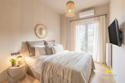 a white bedroom with a bed and a television at Sun-Kissed Boho Haven with Whirlpool Bliss & Patio in Athens
