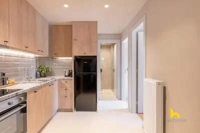 a kitchen with wooden cabinets and a black refrigerator at Sun-Kissed Boho Haven with Whirlpool Bliss & Patio in Athens