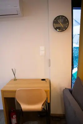 a desk with a chair and a clock on a wall at Zeas Meridian Suite Piraeus Athens in Piraeus