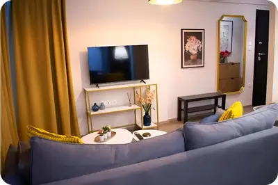 a living room with a blue couch and a tv at Zeas Meridian Suite Piraeus Athens in Piraeus