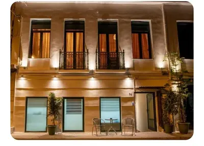 a building with a table and chairs in front of it at Neoclassic Rooms in Athens