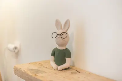 a toy rabbit with glasses sitting on a wooden shelf at The Art Boutique Loft in Athens