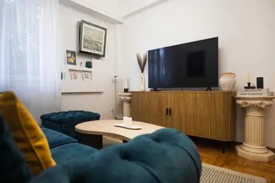 a living room with a tv and a blue couch at Lysé Athens in Athens