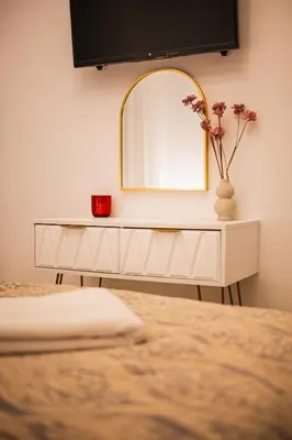 a white dressing table with a mirror and a vase with flowers at Lysé Athens in Athens
