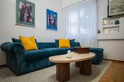a living room with a blue couch and a table at Lysé Athens in Athens