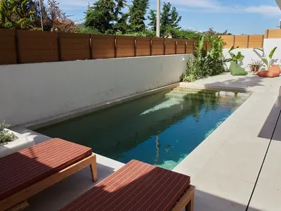 a swimming pool in a backyard with two benches at Camara Athens Riviera Home in Aghia Marina