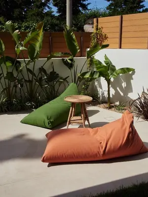 an orange and green pillow next to a stool at Camara Athens Riviera Home in Aghia Marina