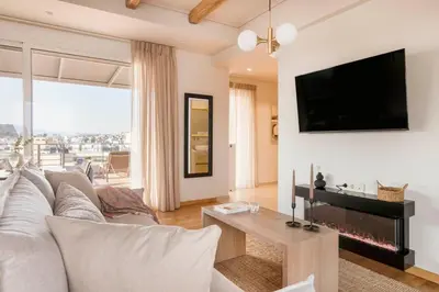 a living room with a couch and a tv on a wall at Panoramic Acropolis View Rooftop Studio by MPS in Athens