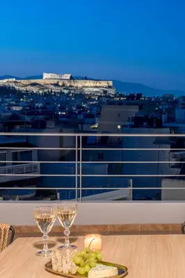 a table with wine glasses and a plate of food at Panoramic Acropolis View Rooftop Studio by MPS in Athens