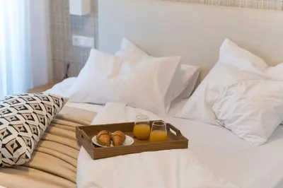 a tray of bread and two glasses of orange juice on a bed at Elliniko Riviera - 2BDRM Apt - Near Metro by MPS in Athens