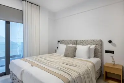 a white bedroom with a large bed and a window at Elliniko Riviera - Family Apt Near Metro by MPS in Athens