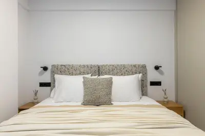 a white bedroom with a large bed with white pillows at Elliniko Riviera - Family Apt Near Metro by MPS in Athens
