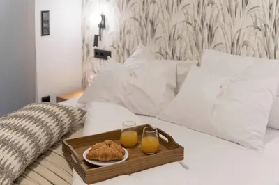 a tray of food and two glasses of orange juice on a bed at Elliniko Riviera - Family Apt Near Metro by MPS in Athens