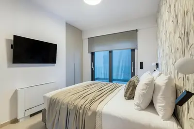 a bedroom with a large bed with a flat screen tv at Elliniko Riviera - Family Apt Near Metro by MPS in Athens