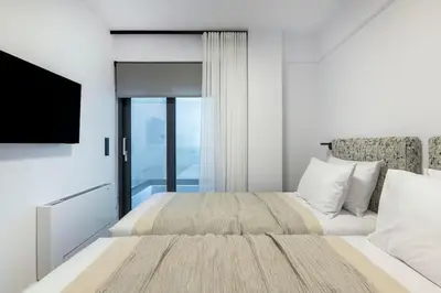 a bedroom with a large bed and a television at Elliniko Riviera - Family Apt Near Metro by MPS in Athens