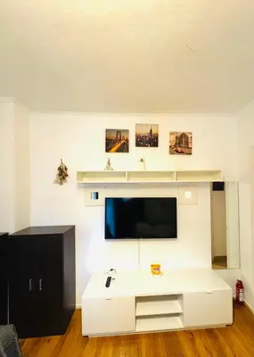 a living room with a tv and a white entertainment center at Athenian Riviera beach apartment in Athens