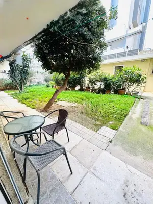 a patio with a table and chairs and a tree at Athenian Riviera beach apartment in Athens